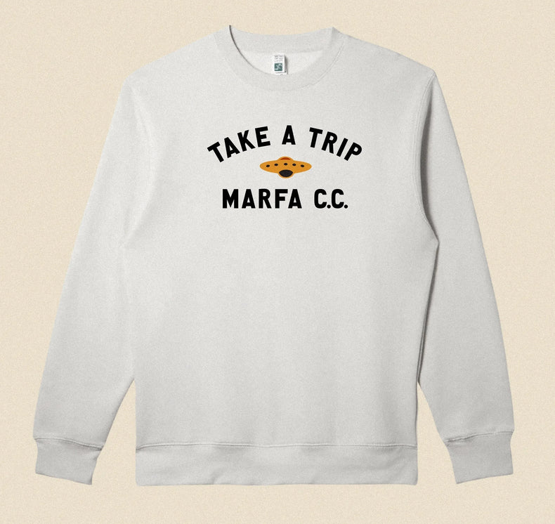 Gray sweatshirt with 'Take a Trip Marfa CC' text on a beige