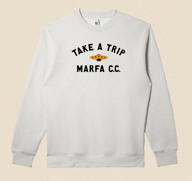 Gray sweatshirt with 'Take a Trip Marfa CC' text on a beige