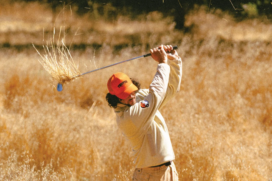 golfer swinging in dry grass field