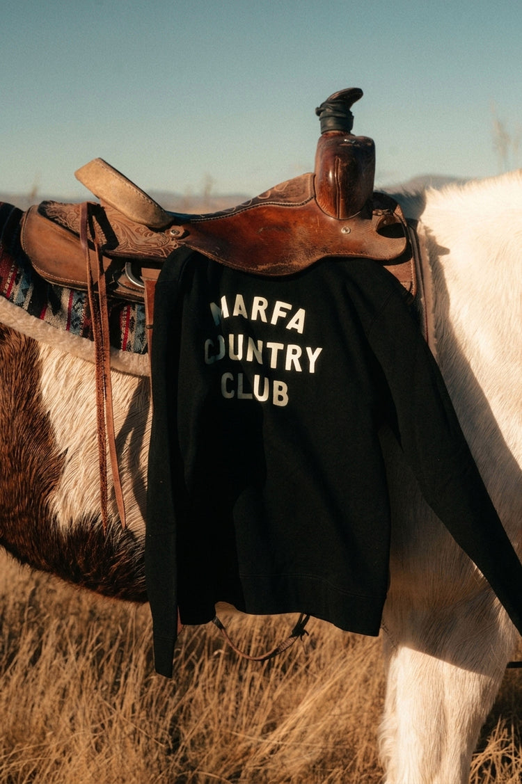 Black Marfa Country Club Club Issue crewneck draped over a western saddle