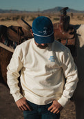 The Rider’s Cap in blue corduroy with white embroidery, worn beside a western saddle